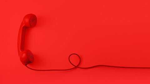Rode telefoon met snoer op een rode achtergrond